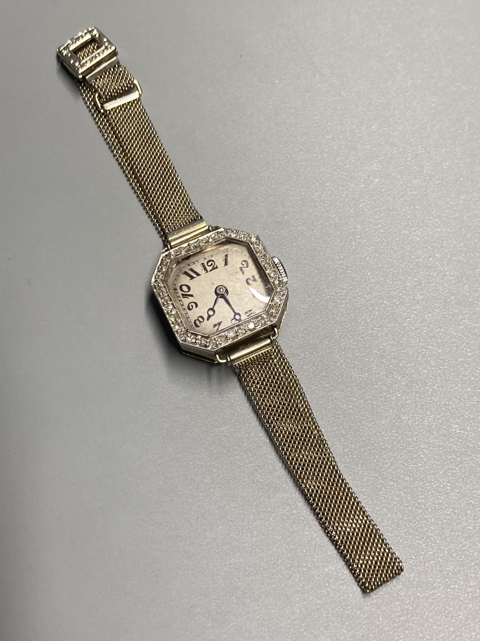 A ladys 1930s white metal and diamond bezel set manual wind wrist watch, on an 18ct mesh link bracelet,